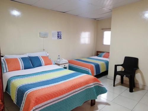 um quarto com duas camas e uma cadeira. em Hostal Cumbres Andinas em Ibarra