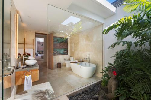 a bathroom with a tub and two sinks and a bath tub at Villa Sanook in Seminyak