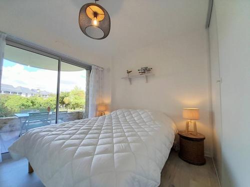 une chambre avec un lit blanc et une grande fenêtre dans l'établissement Carnac : Bel appartement 2 pièces avec terrasse exposée Sud-Est à 500m des plages, parking inclus - FR-1-477-214, à Carnac