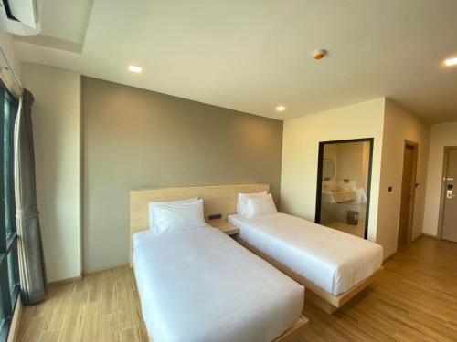 a hotel room with two beds and a mirror at Mayuu Ayutthaya Hotel in Ban Ko Rian