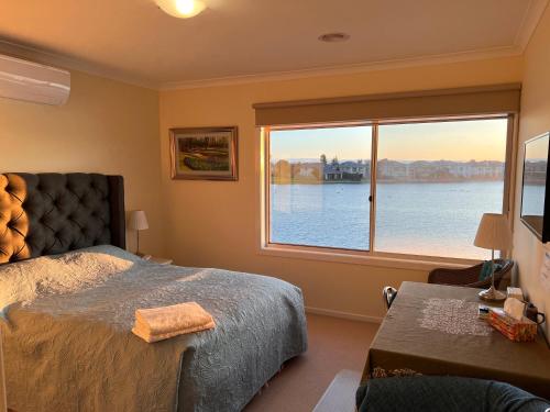 Dormitorio con ventana grande con vistas al agua en King House, en Point Cook