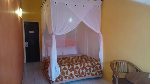 a bedroom with a canopy bed with white curtains at Zen inn in Padangbai