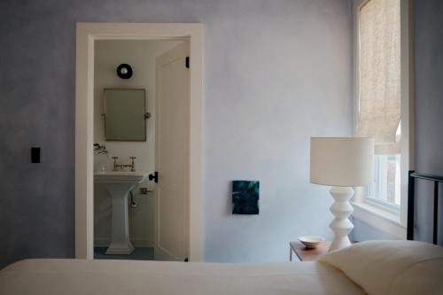 Schlafzimmer mit einem Bett, einem Waschbecken und einem Spiegel in der Unterkunft The James Bradley in Bradley Beach