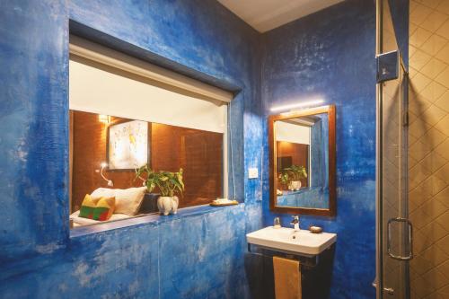 a blue bathroom with a sink and a mirror at AMARA AYURVEDA RETREAT- Overlooking Evergreen Western Ghats an ecologically sustainable living space in Kovalam in Kovalam