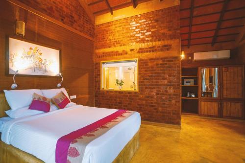 a bedroom with a bed and a brick wall at AMARA AYURVEDA RETREAT- Overlooking Evergreen Western Ghats an ecologically sustainable living space in Kovalam in Kovalam