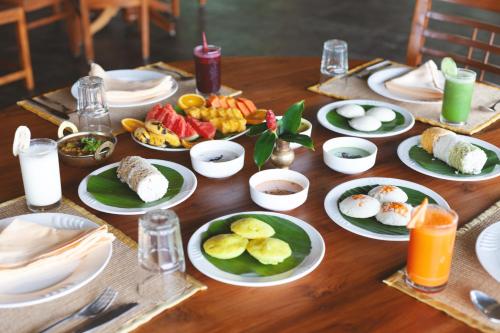 a wooden table with plates of food on it at AMARA AYURVEDA RETREAT- Overlooking Evergreen Western Ghats an ecologically sustainable living space in Kovalam in Kovalam