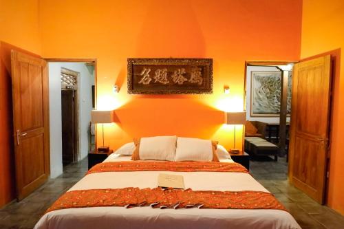 a bedroom with a large bed with an orange wall at D'omah Yogya Hotel in Yogyakarta