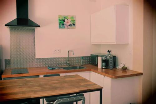 cocina con armarios blancos y encimera de madera en Joli logement centre ville avec clim en Orange