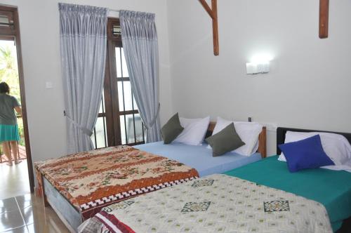 dwa łóżka w pokoju z oknem w obiekcie Traveller's Home Hotel w mieście Tissamaharama