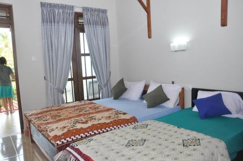 two beds in a room with a window at Traveller's Home Hotel in Tissamaharama