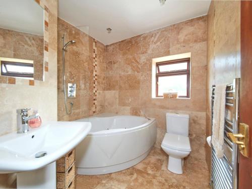 a bathroom with a tub and a toilet and a sink at Millie's Cottage in Oldham