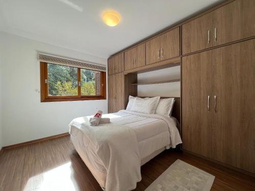 1 dormitorio con 1 cama grande y armarios de madera en Vista do Quilombo 204B - Apartamento no Centro de Gramado, en Gramado