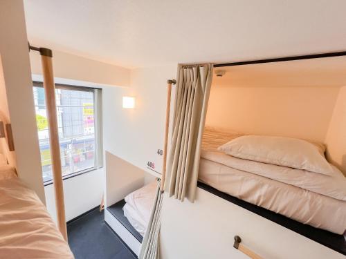een kleine slaapkamer met 2 bedden en een raam bij Osaka Nipponbashi EVISU HOSTEL in Osaka