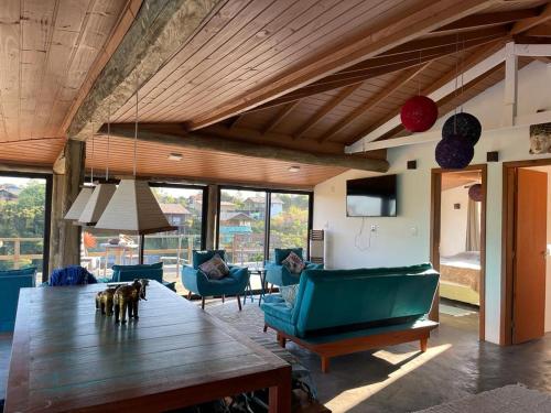 ein Wohnzimmer mit einem großen Holztisch und blauen Sofas in der Unterkunft Villa Santorini Praia do Rosa com piscina e jacuzzi in Praia do Rosa
