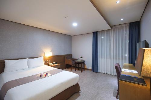 een hotelkamer met een groot bed en een televisie bij Benikea Hotel Jeju in Jeju-stad