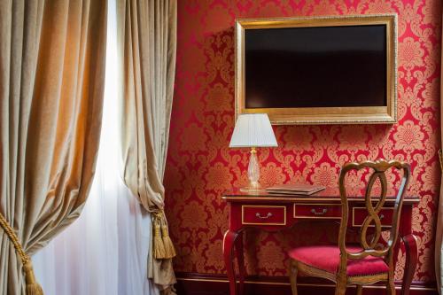a room with a desk with a lamp and a chair at Hotel Ai Reali - Small Luxury Hotels of the World in Venice
