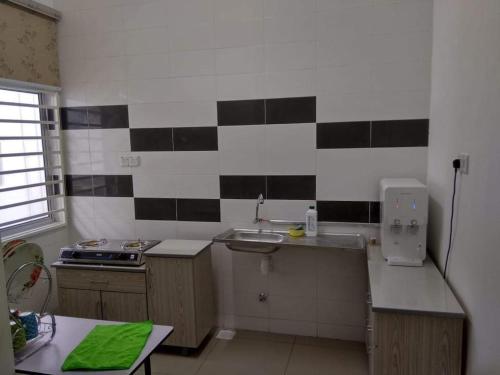 uma cozinha com azulejos pretos e brancos na parede em FENDIONYA CORAL em Porto Dickson