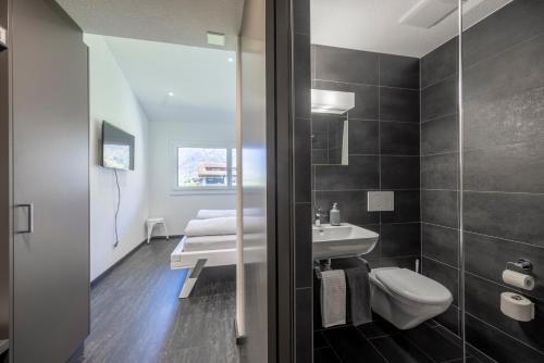 uma casa de banho com um WC branco e um lavatório. em Moto-Center BeO AG (Bike & Bed) em Brienz
