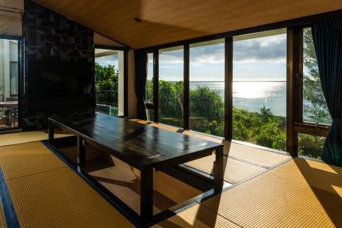 a room with a table with a view of the ocean at The Peridot Smart Hotel Tancha Ward in Onna