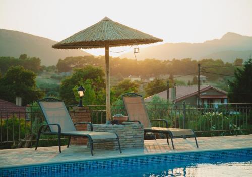 two chairs and an umbrella next to a swimming pool at Villa “Alexis&Coco” traditional house in Tríkorfon