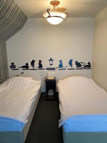 two beds in a room with birds on the wall at Oyado Cocochi in Tokyo