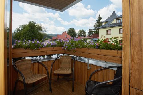 two chairs on a balcony with a view of flowers at Apartment Rezidence - Javor & Wellness in Železná Ruda