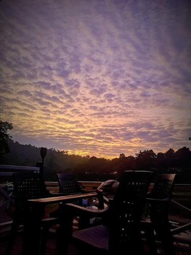 a sunset on a patio with tables and chairs at Wild Lodge Taman Negara in Kuala Tahan