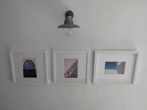 four pictures on a white wall with a lamp at Latmos 1860 in Skala