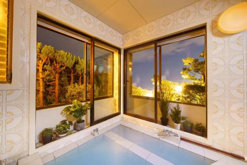 a swimming pool in a room with windows at Bay view Sotetsu no yu in Beppu