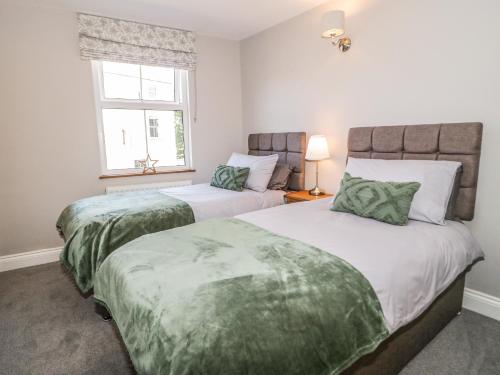 two twin beds in a room with a window at Millgate House in Conwy