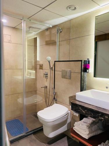 a bathroom with a toilet and a shower and a sink at Royal Plaza Suites by RAK Rooms, Mangaluru in Mangalore
