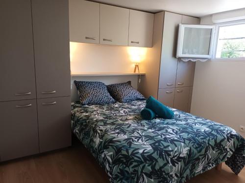 Dormitorio pequeño con cama con almohadas azules en Gîte du jardin de Charlotte - Ancenis St Géréon, en Saint-Géréon