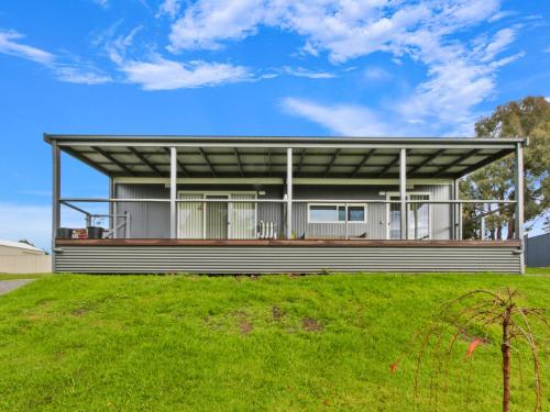 a house with a metal roof on top of a yard at Swans View in Metung