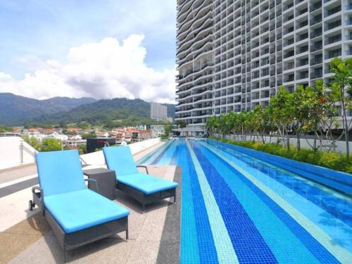a swimming pool with blue chairs on the roof of a building at Deluxe Seaview Suite Twin Bed by The Only Bnb in Tanjong Tokong