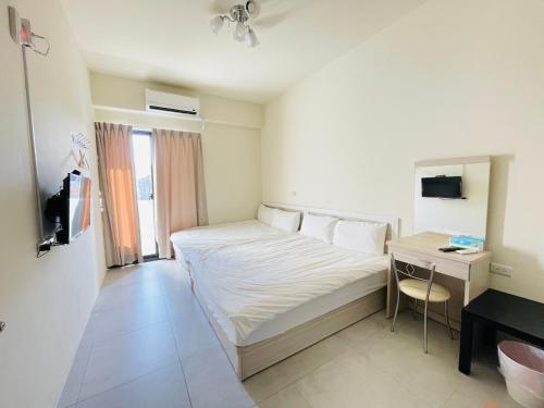 a hotel room with a bed and a desk and a bed at Penghu Happy House in Magong