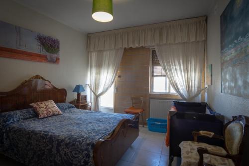 a bedroom with a bed and a chair and a window at Casa rural Arribes Vida in Vitigudino