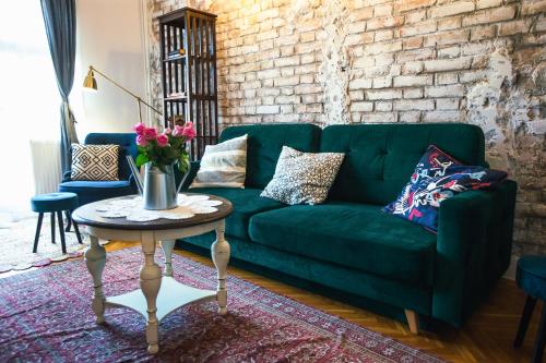 a green couch in a living room with a table at Villa Inda Rooms in Eger