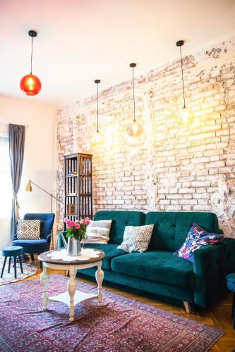 a living room with a green couch and a brick wall at Villa Inda Rooms in Eger