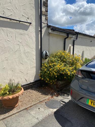 a car parked next to a house with flowers at Whitton Lodge B&B in Chesterfield