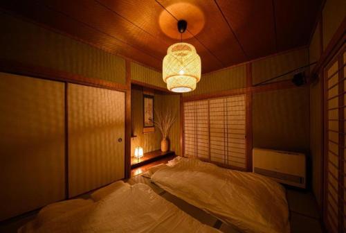 sypialnia z dużym łóżkiem i żyrandolem w obiekcie Taketori Roten -House with open-air bath w mieście Beppu
