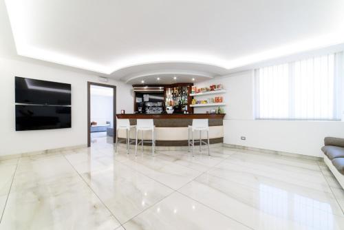 a white living room with a bar with stools at Hotel La Mela in Varcaturo