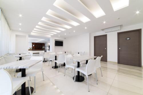 a dining room with white tables and white chairs at Hotel La Mela in Varcaturo
