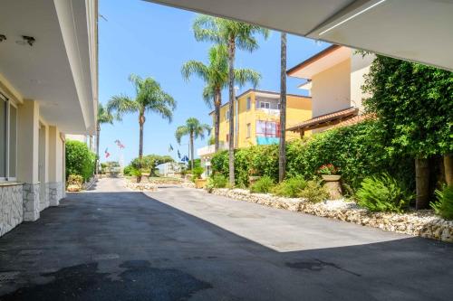 an empty street with palm trees and a building at Hotel La Mela in Varcaturo