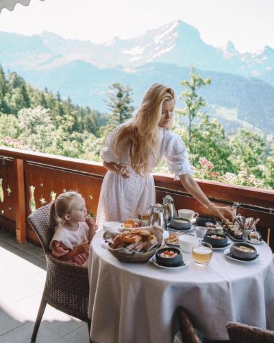 a woman and a little girl sitting at a table with food at Chalet RoyAlp Hôtel & Spa in Villars-sur-Ollon