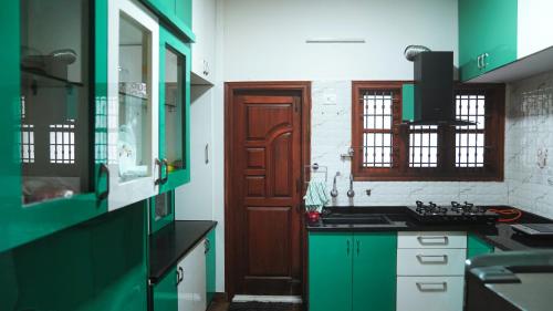 a kitchen with green cabinets and a brown door at Padmanivas in Bangalore