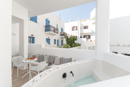 um apartamento branco com uma varanda com uma mesa e cadeiras em Naxian Spirit Inn em Naxos Chora