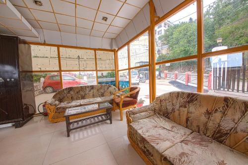 a living room with two couches and large windows at FabExpress Sapphire in Mussoorie