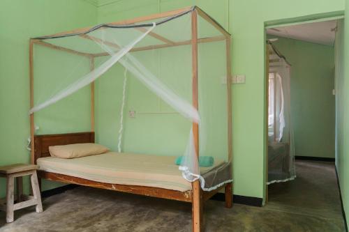 a bed with a canopy in a room at Little Bay Arugam Bay in Arugam Bay