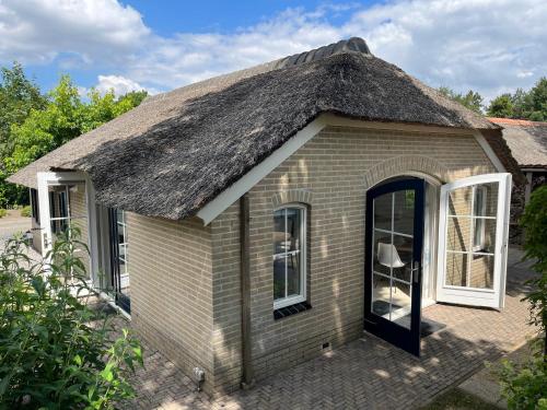 a small house with a thatched roof at Villa Clementine with sauna in Ermelo in Ermelo