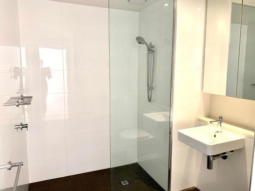 y baño blanco con lavabo y ducha. en Serenity Zealandia - Luxury 1brm unit at Darwin Waterfront en Darwin